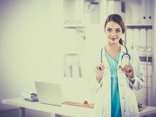 Retrato de una joven doctora con una bata blanca de pie en el hospital —  Fotos de Stock