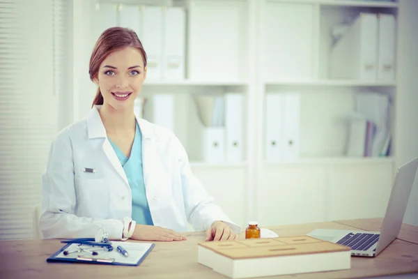 Женщина-врач сидит за столом и работает с ноутбуком в хости — стоковое фото