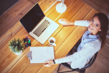 Masada oturan genç bir kadın.