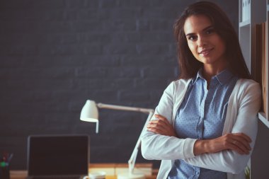 Dizüstü bilgisayarının yanında duran genç bir kadın.