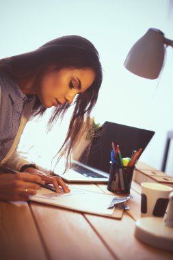 Masada oturan genç bir kadın.