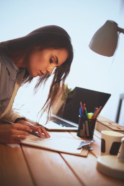 Masada oturan genç bir kadın.