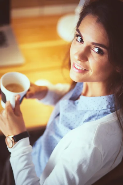 Portrait of relaxed young woman sitting at her desk holding cup of coffee — Stock Photo, Image