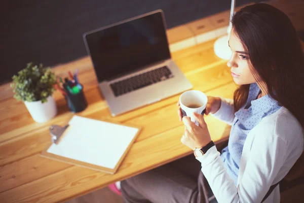 Portrait de jeune femme détendue assise à son bureau tenant une tasse de café — Photo