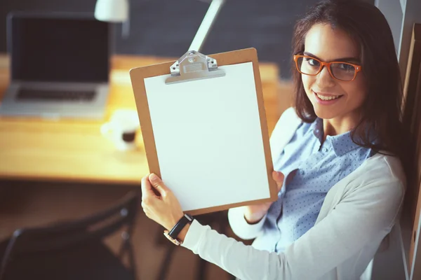 Jeune femme debout près du bureau avec le dossier de tenue d'ordinateur portable — Photo