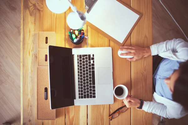 Jeune femme travaillant assise à un bureau — Photo