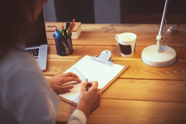 Jeune femme travaillant assise à un bureau — Photo