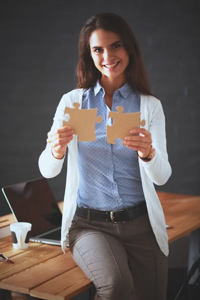 Geschäftsfrau hält und zeigt auf ein Puzzleteil — Stockfoto