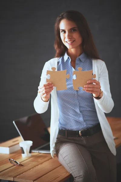 Geschäftsfrau hält und zeigt auf ein Puzzleteil — Stockfoto
