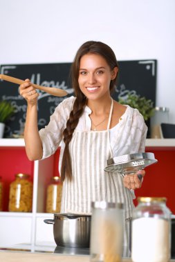 Mutfakta ahşap kaşıkla yemek pişiren kadın