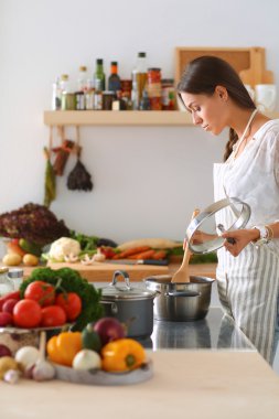 Mutfakta ahşap kaşıkla yemek pişiren kadın
