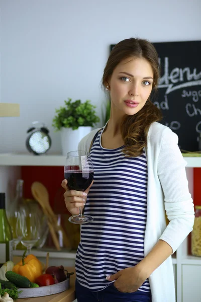 Mujer bonita bebiendo un poco de vino en casa en la cocina . —  Fotos de Stock