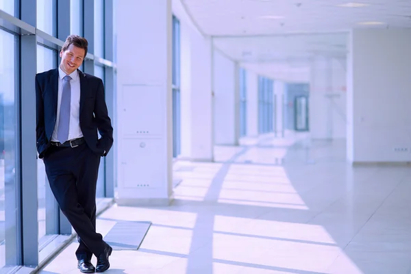 Framgångsrik affärsman står i korridoren hans företag nära fönster — Stockfoto