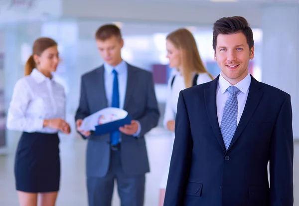 Jungunternehmer diskutiert mit Teamkollegen im Hintergrund — Stockfoto