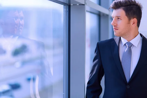 Erfolgreicher Geschäftsmann steht im Hausflur seiner Firma am Fenster — Stockfoto