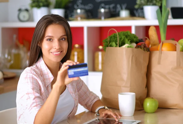 Smiling woman online shopping using tablet and credit card in kitchen — Stock Photo, Image