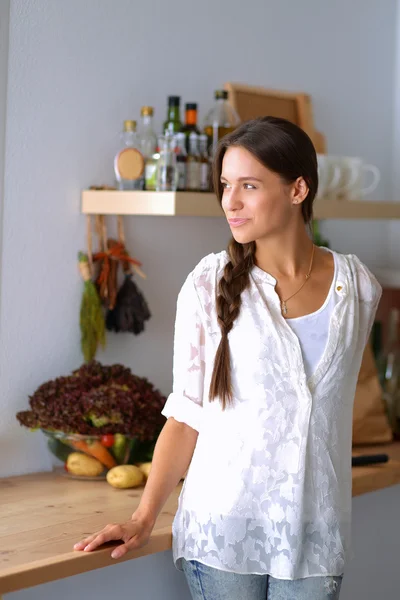 Молодая женщина, стоящая возле стола на кухне — стоковое фото