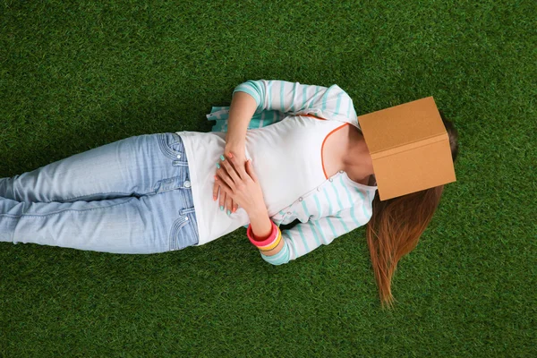 Girl lying on the grass covering the face of the book — Stock Photo, Image