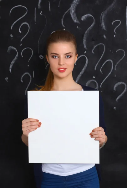 Young girl with question mark holding a blank on gray background — Stock Photo, Image