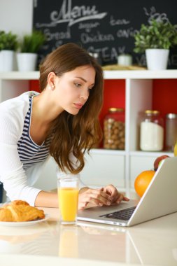 Genç bayan mutfakta masanın yanında oturuyor.