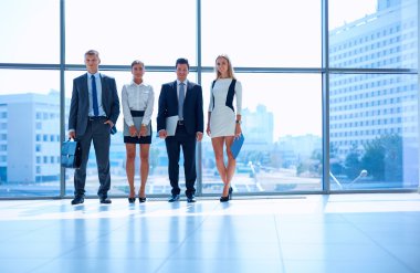 Modern ofis lobisinde duran genç iş adamları.