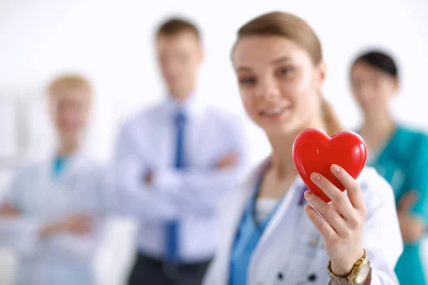 Mujer joven doctora sosteniendo un corazón rojo, aislado sobre fondo blanco — Foto de Stock