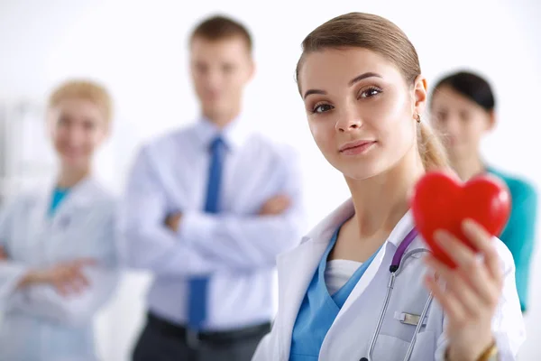 Mladá žena lékař drží červené srdce, izolované na bílém pozadí — Stock fotografie