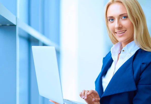 Femme d'affaires debout contre la fenêtre de bureau tenant ordinateur portable — Photo