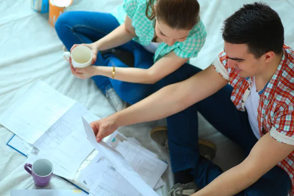 Pareja joven sentada en el suelo y calculando sobre sus ahorros — Foto de Stock