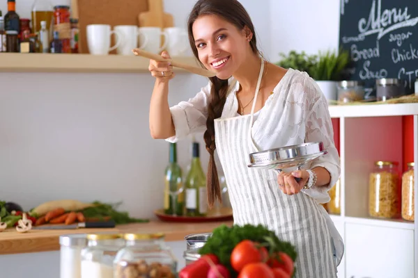 Jeune femme debout près de la cuisinière dans la cuisine — Photo