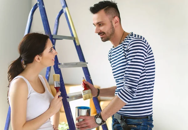 Retrato feliz sorrindo jovem casal pintura parede interior da nova casa — Fotografia de Stock