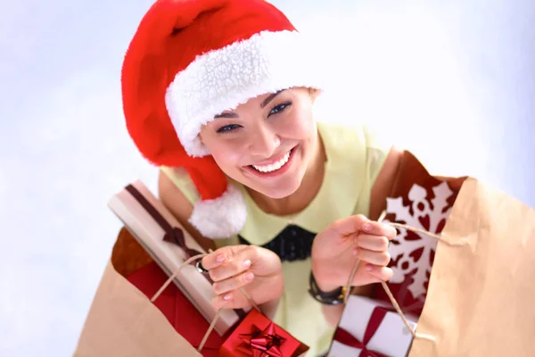 Mulher sorridente em chapéu de santa com muitas caixas de presente no fundo branco — Fotografia de Stock