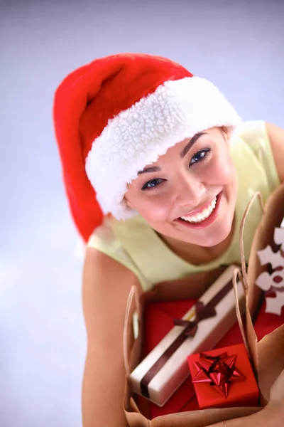 Mujer sonriente en sombrero de santa con muchas cajas de regalo sobre fondo blanco —  Fotos de Stock