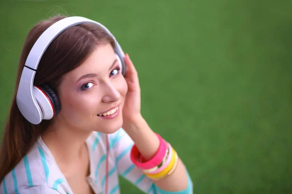 Mujer escuchando la música sentada sobre hierba verde — Foto de Stock