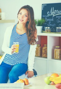 Genç bayan mutfakta masanın yanında oturuyor.