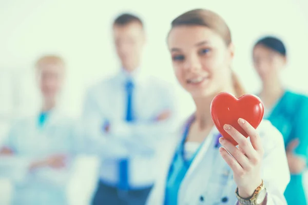 Young woman doctor holding a red heart, isolated on white background