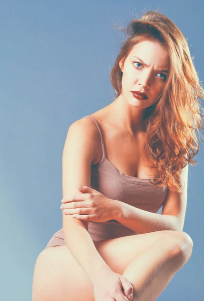 Beautiful barefoot woman sitting on the floor — Stock Photo, Image