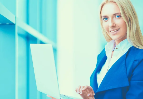 Mujer de negocios de pie contra la ventana de la oficina celebración de ordenador portátil — Foto de Stock