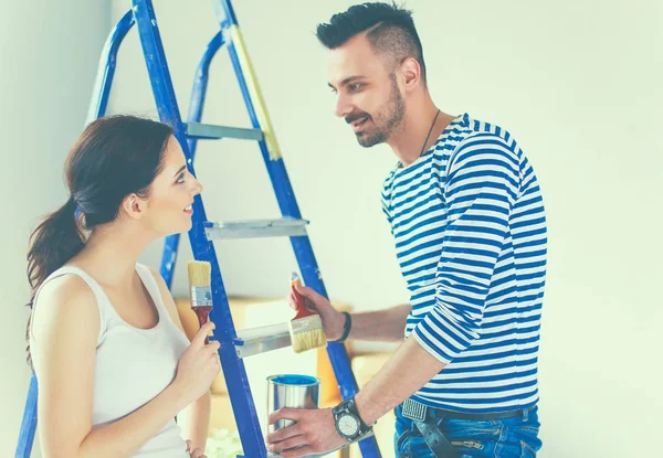 Retrato feliz sorrindo jovem casal pintura parede interior da nova casa — Fotografia de Stock