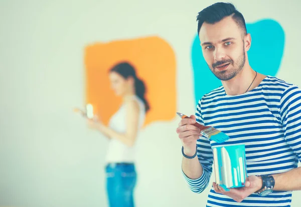 Portret gelukkig lachend jong koppel schilderij interieur wand van nieuwe huis — Stockfoto