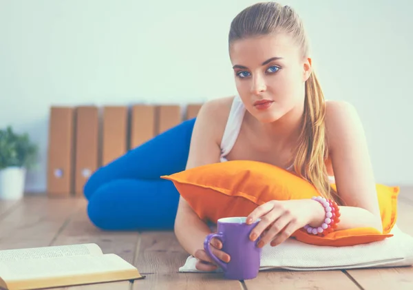 Smiling young woman lying on a white floor with pillow — Stock Photo, Image