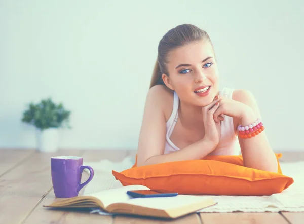 Lachende jonge vrouw liggend op een witte vloer met kussen — Stockfoto