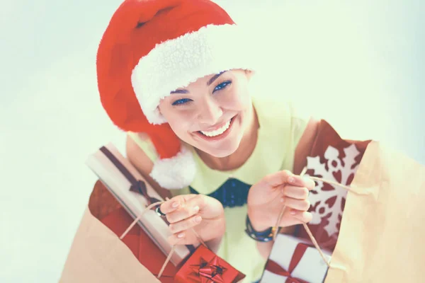 Femme souriante en santa chapeau avec de nombreuses boîtes-cadeaux sur fond blanc — Photo