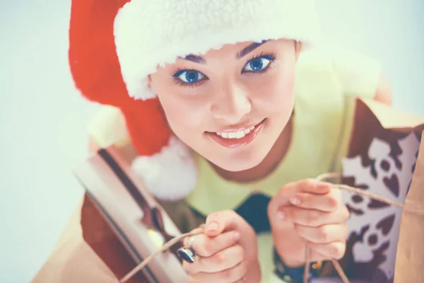 微笑在圣诞老人的帽子，与很多礼品盒白色背景上的女人 — 图库照片