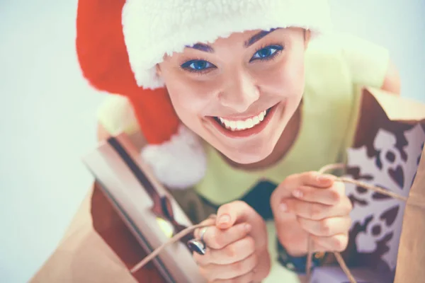 Mulher sorridente em chapéu de santa com muitas caixas de presente no fundo branco — Fotografia de Stock