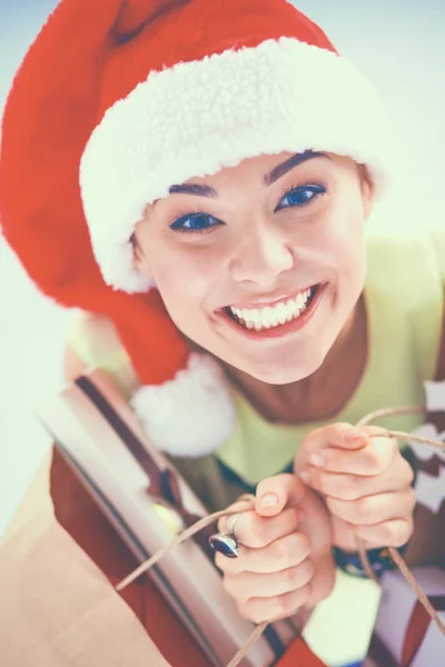 Mulher sorridente em chapéu de santa com muitas caixas de presente no fundo branco — Fotografia de Stock