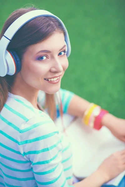 Kvinna som lyssnar på musik sitter på grönt gräs — Stockfoto