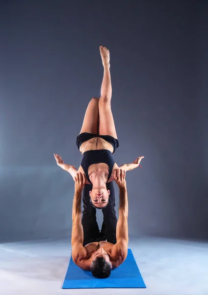 Pareja joven practicando acro yoga en estera en estudio juntos — Foto de Stock