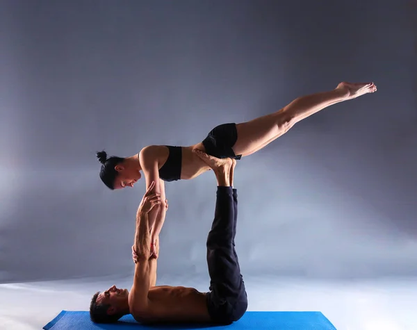 Νεαρό ζευγάρι εξάσκηση acro yoga σε χαλί στο στούντιο μαζί — Φωτογραφία Αρχείου