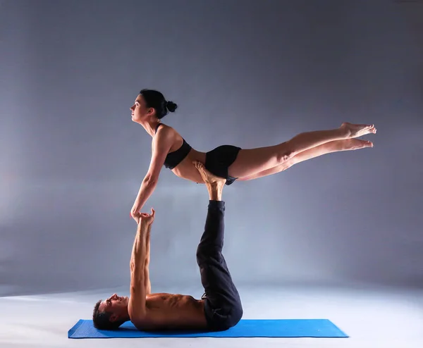 Νεαρό ζευγάρι εξάσκηση acro yoga σε χαλί στο στούντιο μαζί — Φωτογραφία Αρχείου